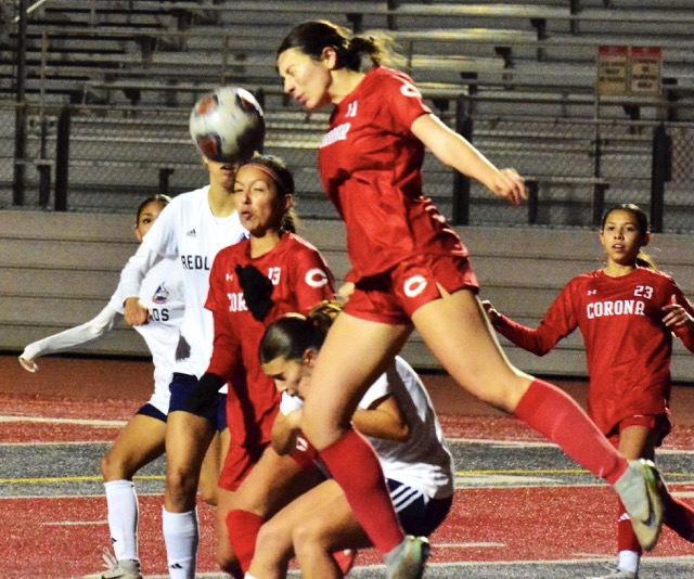 Corona’s Vanessa Diaz (11) leaps for a header as teammate Giselle Fuentes-Gonzalez (13) reflexes.