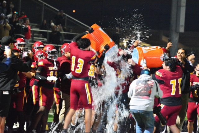 Hillcrest players Ray Causey (13) and Justin Escalante (77) are amongst players providing the celebratory dousing of Head Coach Travis Carter (center) after the Trojans defeated the Tahquitz Titans 63 – 34 in the CIF Division 10 Title game. The football program, which began with a freshman squad upon the school’s opening in 2012, captured its first CIF football championship. 