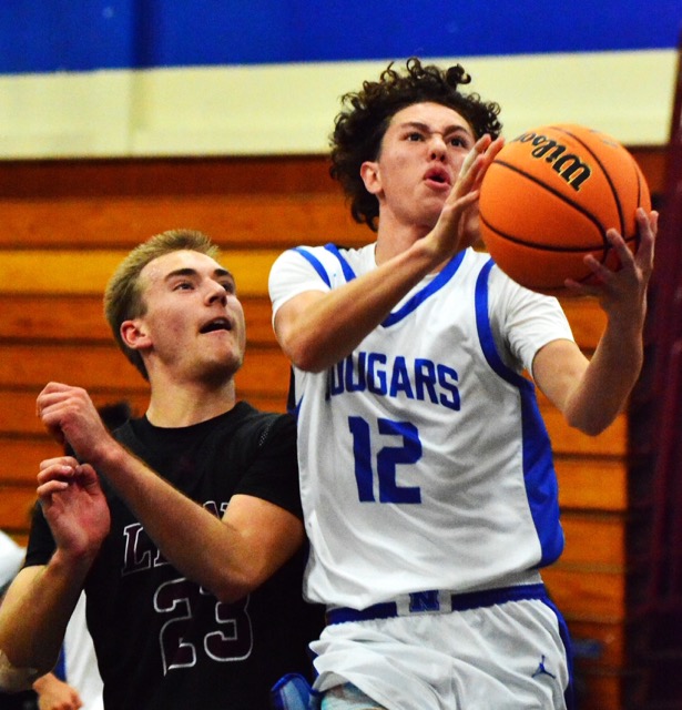 Norco’s Nyjah Rasmussen (12) scores on a layup over Arlington’s William Shannon (23) during the Lions 75 – 62 victory over the Cougars.
