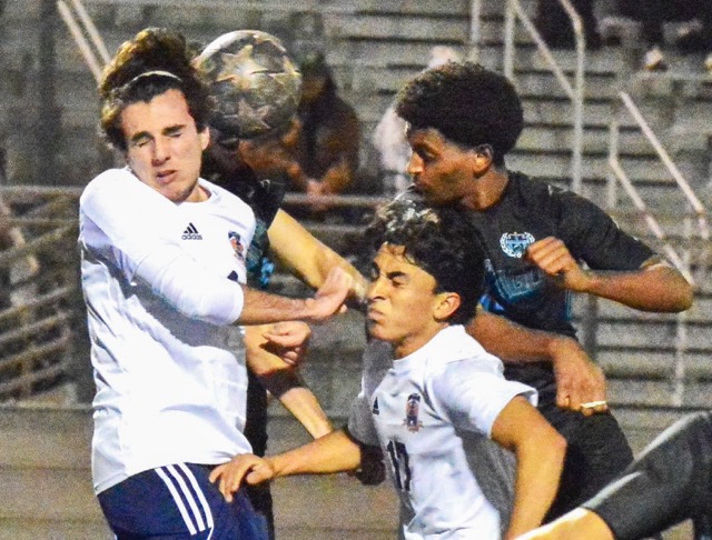 Eastvale Roosevelt’s Lucca Failla (left) clears a corner kick off his face while Jason Hernandez (center) and Santiago’s Sameson Gizaw (right) leap for the ball.