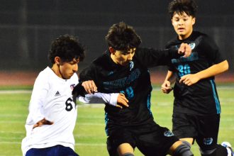 Eastvale Roosevelt’s Eduardo Nuno (6) and Corona Santiago’s Nathan Navarijo (center) battle for the ball while Edgar Regalado (30) pursues the play during the Sharks 2 – 1 victory over the Mustangs.