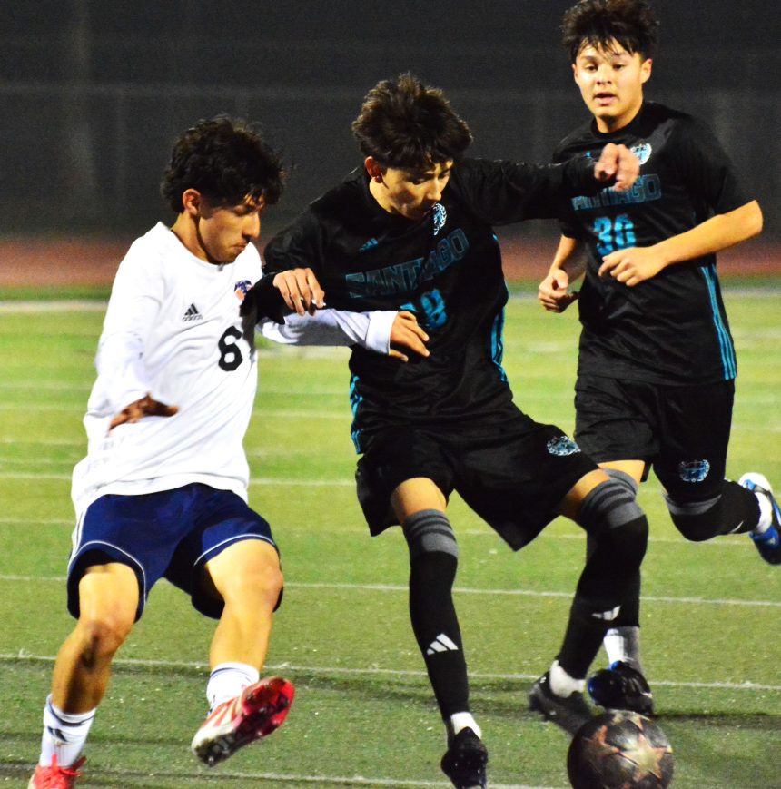 Eastvale Roosevelt’s Eduardo Nuno (6) and Corona Santiago’s Nathan Navarijo (center) battle for the ball while Edgar Regalado (30) pursues the play during the Sharks 2 – 1 victory over the Mustangs.