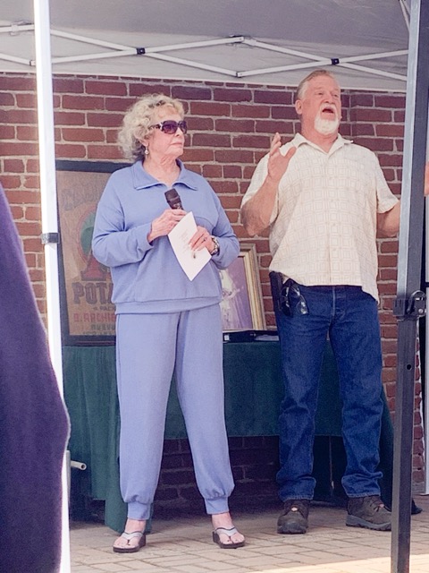 Beverly Archibeck, Ben Sr.’s granddaughter, and Brian Smith, Adrian’s husband, speak in front of the framed Archibeck potato sack, Ben Sr. and “Momacita’s” wedding photo, and a book of the Archibeck's history dating back to the births of Ben Sr. in New Mexico and his Momacita’s in Mexico.