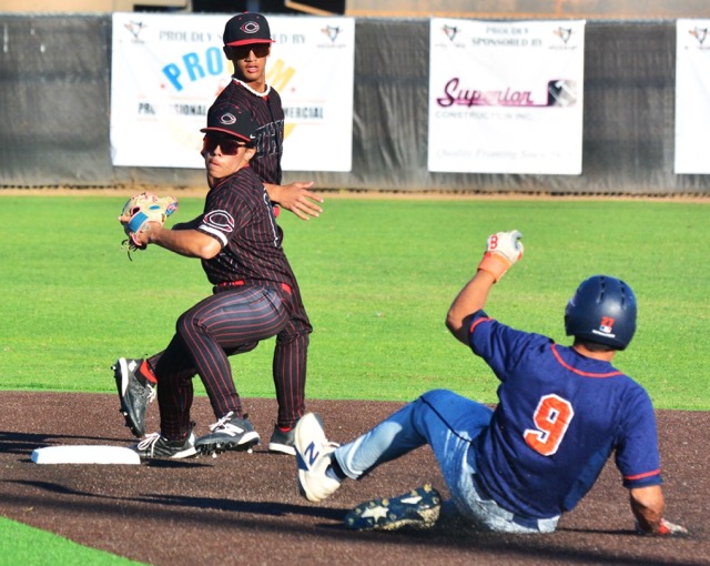 Corona Centennial second baseman AJ Almaraz (on bag) has received the flip from shortstop Ethan Miller (background) and fires to first for the double play as Roosevelt’s Travis Anderson (9) slides towards the base. The Huskies handled the Mustangs 19 – 3.