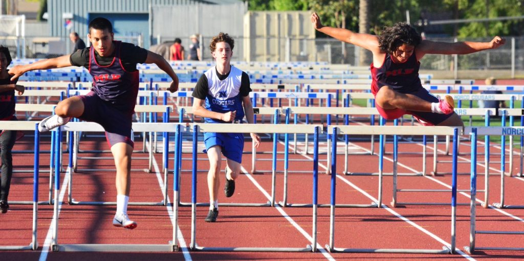 Riverside King’s Cruz Yslas at 19:20 (left) and Tristan Lepale at 19:39 (right) lead Norco’s Gavin Roberts 20:27 (center) in the junior varsity boys’ hurdles.
