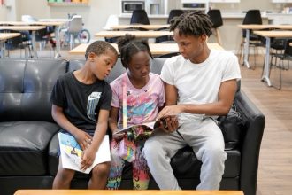 Reading Scores. Karter Hardeman, 7, left, and Janayla Ralsey, 8, center, read with volunteer Joshua Banks, right, during an after-school literacy program through the Pure Hope Project in Atlanta on Thursday, April 6, 2023.  Credit: AP Photo/Alex Slitz
