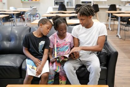 Reading Scores. Karter Hardeman, 7, left, and Janayla Ralsey, 8, center, read with volunteer Joshua Banks, right, during an after-school literacy program through the Pure Hope Project in Atlanta on Thursday, April 6, 2023.  Credit: AP Photo/Alex Slitz