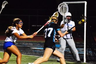 Santiago’s Gracie Weinrich (37) gets ready to shoot on goal while Norco’s Makayla Pacheco (left) and goalie Eliana Rodriguez (right) defend. The Sharks beat the Cougars 13 – 3.