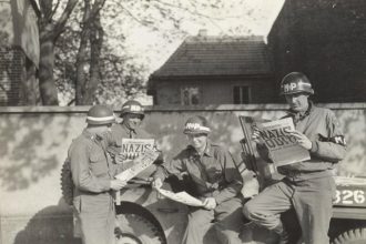 May 8. Four MPs take a break along a German road to read in the "Stars and Stripes" newspaper about the Nazi surrender. Credit: U.S.Army