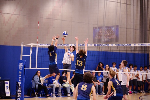 Temescal Canyon’s Riley Patterson (#11) challenges Santa Rosa Academy’s Dominic Thomas (#1) at the tape. The match was a defensive battle, with both teams fighting for every inch at the net in front of a packed Titan gym.