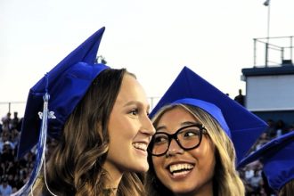 Maile Buckmiller (left) and Sinclair Smith (right) smile as they watch their Norco High Class of 2026 get their diplomas during the graduation ceremony.