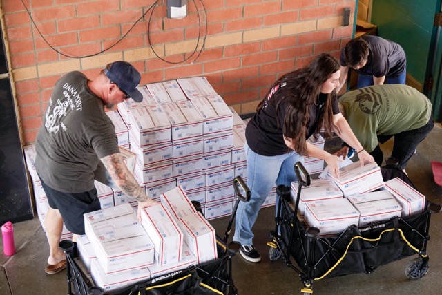MilVet volunteers load heavy stacks of completed care packages into carts to manually transport them to the waiting trucks at the end of the event.