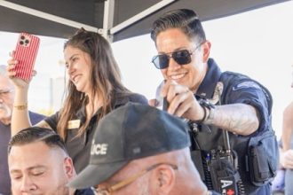 Lieutenant Christina Reveles,standing with sunglasses, plays “Eye of the Tiger” from her phone to encourage MPD to the win. Credit: Photo by Lisa Zambrano
