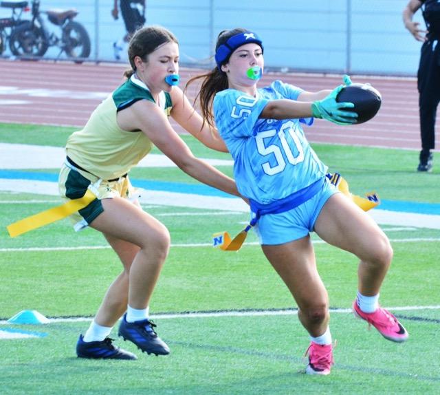 Norco’s Brooklyn Rivera (50) stretches the ball toward the goal line for a touchdown while a Lake Elsinore Lakeside defender reaches futilely for her flag.  The Cougars blanked the Lancers 41 – 0.