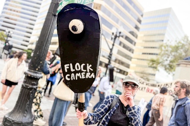 Flock. California lawmakers have tried and failed five times since 2022 to regulate technology that tracks license plates. Meanwhile, a national backlash against the tech has gained momentum. A protester holds a sign while demonstrating on the corner of Broadway and 14th Street in Oakland on Aug. 20, 2026. Protesters gathered to call for a ban on automated license plate reader technology.  Credit: Photo by Khari Johnson, CalMatters