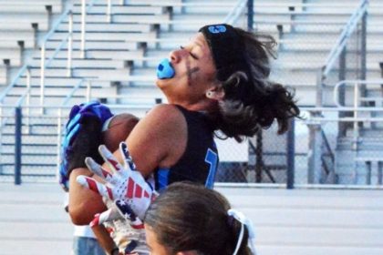 Corona Santiago’s Jianna Simien (13) leaps for a catch and gets hit by El Modena’s Brooklyn Calderon (44) during the Sharks’ 27 – 12 victory over the Vanguards.