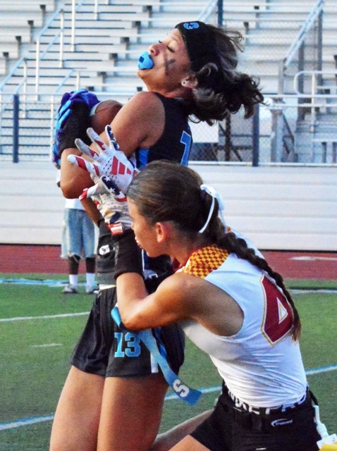 Corona Santiago’s Jianna Simien (13) leaps for a catch and gets hit by El Modena’s Brooklyn Calderon (44) during the Sharks’ 27 – 12 victory over the Vanguards.