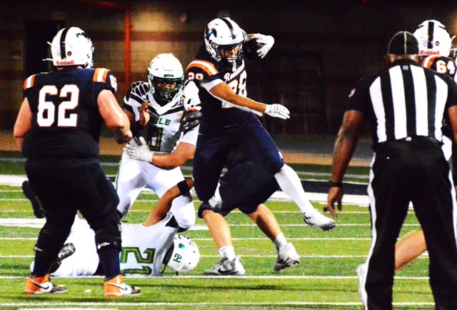 Eastvale Roosevelt’s Nolan Chan (28) leaps over Palmdale’s Aidan Vides (21) while Drake Wilson (62) and Derek DeSeife (64) look to block. The Mustangs defeated the Falcons 41 – 20.