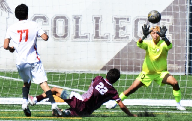 Long Beach’s Steven Sorto (77) blasts a shot on goal as Norco’s James Solek (22) slides to block it and goalie Kaisei Nakamura (00) is ready to deflect the volley.