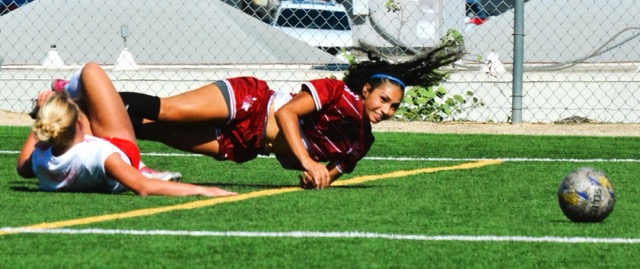 Palomar College’s Lorelai Jimerson (White) has taken out Norco’s Naidelin Torres (Maroon), who watches the ball roll away during the Mustangs’ 1 – 0 victory over the Comets.