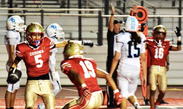 Corona’s Nico Mejia (5) gets ready to celebrate his touchdown catch with Giovanni Gutierrez (19) after San Gorgonio defender Aaden Rojas (11) deflected the toss right to Mejia. Dominic Pickens (16) and the referee signal touchdown while the defenders are stunned by the result.