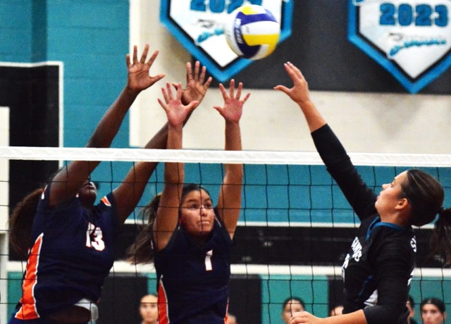 Eastvale Roosevelt’s Jordan Rall (13) and Ellie Delatorre (1) leap to stop a volley over the net by Santiago’s Madelyn Siqueland (right) during the Mustangs 3 – 1 win over the Sharks.