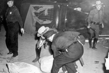 September 4. Police move heavy rocks from roadway near picnic grove in Peekskill, New York, Aug. 27, 1949 after rioting broke out at concert scheduled by singer Paul Robeson. Overturned automobile is in background. (AP Photo)
