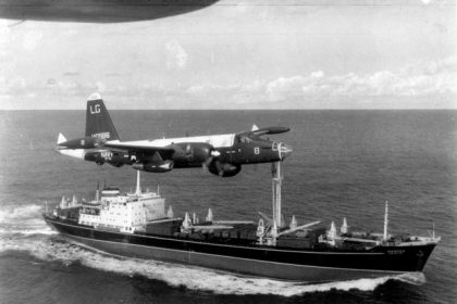 October 16. A US Navy P-2H Neptune of VP-18 flying over a Soviet cargo ship with crated Il-28 Bombers on deck during the Cuban Crisis. Credit: USN