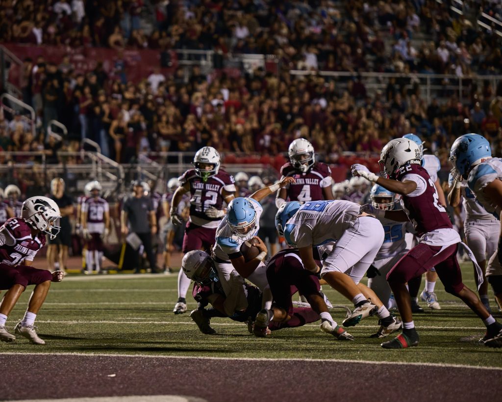 Liberty’s RB, Nathan Ayala #12, fights through a pile of Paloma Valley defenders before being brought down just short of the goal line.