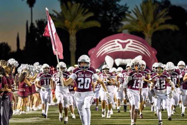 Paloma Valley’s Antonio Castellon (#20) leads the wildcats onto the field before their Varsity football game against Perris High School
